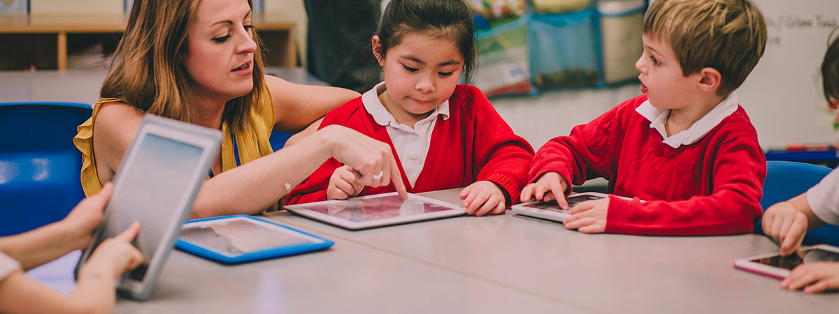 Young Children At Desk With Teacher